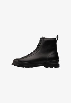 Bottines en cuir noir avec un bout arrondi, un design à lacets et une finition texturée. Présente un onglet de tirage et une semelle en caoutchouc robuste.