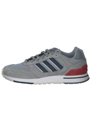 Scarpa sportiva grigia con tomaia in suede e mesh, tre strisce navy, lacci grigi, accento rosso sul tallone e suola in gomma bianca con motivo antiscivolo.