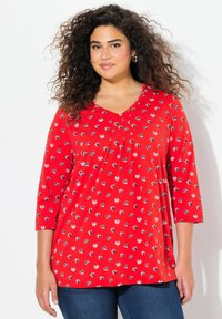Rotes Baumwolloberteil mit V-Ausschnitt, Dreiviertelärmeln und floralem Muster in Schwarz und Weiß. Verfügt über Falten unterhalb des Ausschnitts.