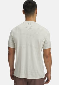 Gaišs pelēks sporta krekls ar perforētu dizainu, īsām piedurknēm un apaļu dekoltē. Under Armour logo aizmugurē.