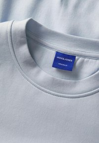 Ljusblå bomulls t-shirt med rund halsringning och sömdetaljer, märkt "JACK & JONES" på en blå etikett. Mjuk textur.
