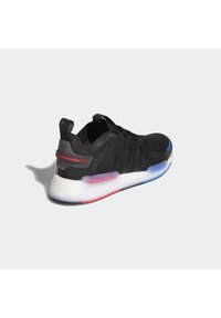 Black athletic shoe with a mesh upper, textured accents, and a white cushioned midsole with red and blue translucent details.