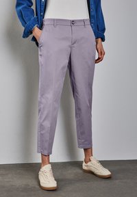 Ljus lavendelfärgade chinos med slim fit, framfickor och knappstängning. Bärs med en denimskjorta och krämfärgade strukturerade sneakers.