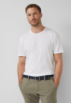 Witte T-shirt met korte mouwen, gecombineerd met olijfgroene broeken en een marineblauwe riem met zilveren accenten. Eenvoudig, casual ontwerp met een relaxte pasvorm.