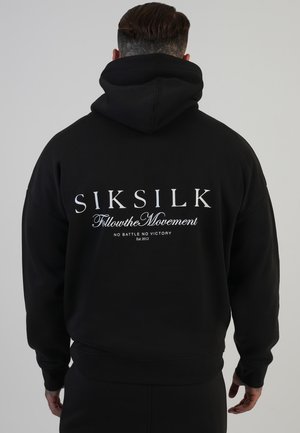 Schwarzer Hoodie mit einem großen weißen Druck auf der Rückseite. Verfügt über eine Kapuze mit Kordelzug, gerippte Bündchen und eine lockere Passform.