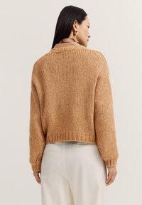 Gekürzter, gestrickter Pullover in einem warmen Beige-Ton. Verfügt über einen lockeren Schnitt, gerippten Saum und weite Ärmel. Die strukturierte Wolle sorgt für Tiefe.