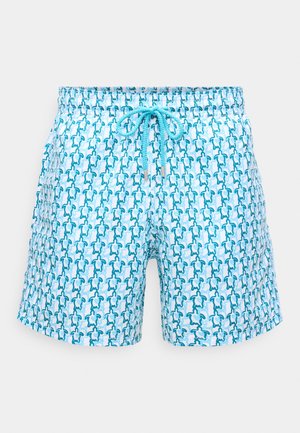 Pantaloni de baie de un albastru deschis, cu o talie ajustabilă prin șnur și un model repetitiv de mici broaște țestoase de culoare teal închis și albastru deschis.