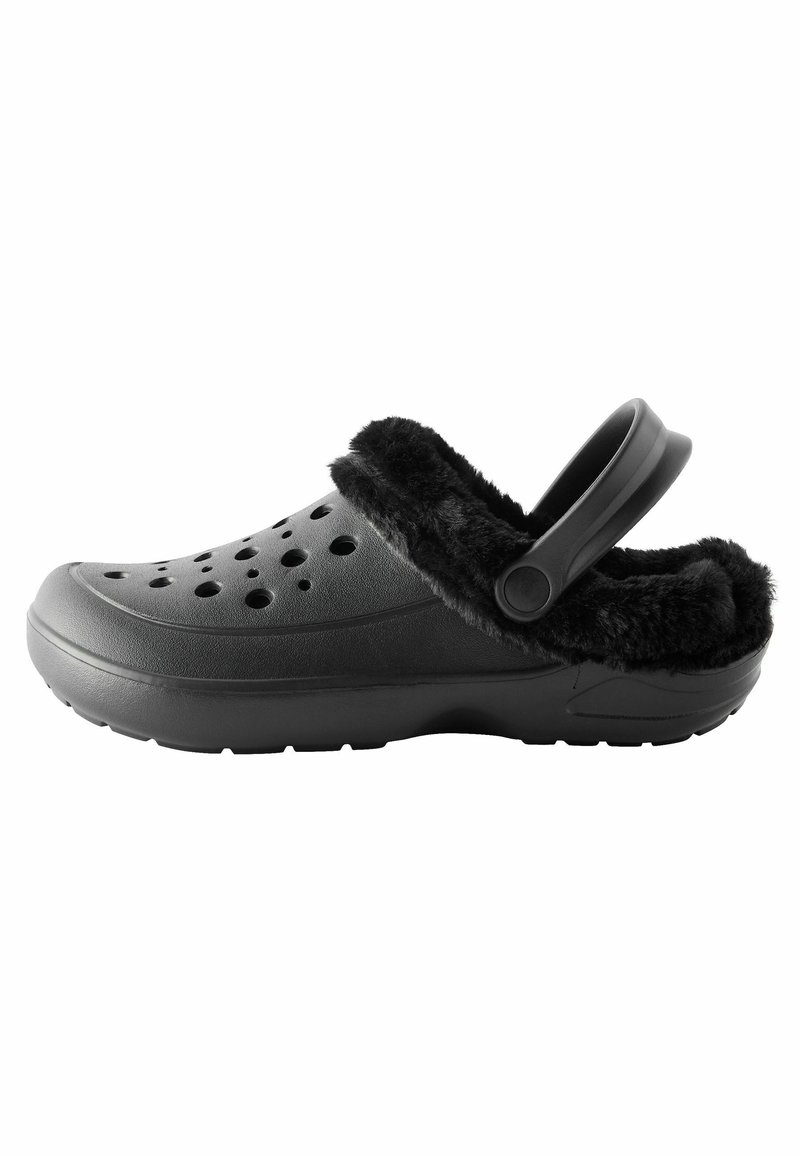 Schwarze Clogs mit weichem schwarzen Fellfutter, belüfteten Löchern entlang der Oberseite und einem hinteren Riemen für einen sicheren Sitz. Strukturierte Gummisohle.