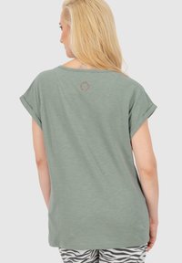 T-shirt a maniche corte color verde oliva con vestibilità rilassata, dotato di un logo rotondo sul retro. Tessuto morbido e design casual.