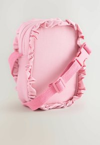 Rosa tygaxelväska med volangkant, dragkedjestängning och ett vävt band med plastspänne. Slät textur och kompakt design.
