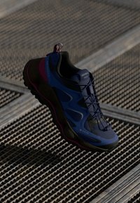 Blaue und schwarze Sportschuhe mit einer strukturierten Oberseite, leichtem Design, rosa Akzenten und einem GORE-TEX-Label, ausgestattet mit einer robusten Sohle.