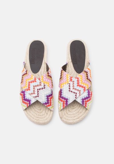 Paire de sandales plates avec des semelles tissées beiges et des lanières en tissu coloré à motifs zigzag se croisant à l'avant.