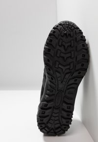 Black athletic shoe sole with deep tread patterns, made of rubber, featuring textured grooves for grip and stability. Minimalist design.