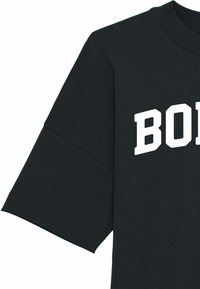 Juodas medvilnės marškinėliai, pasižymintys ryškiu baltu spaudiniu su žodžiu "BORN". Turi klasikinį apvalų kaklą ir trumpas rankoves.