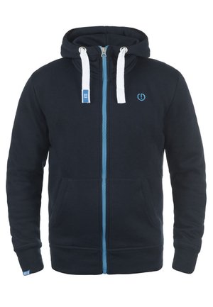 Sudadera con cremallera en color navy, hecha de una tela suave, con una cremallera azul, cordones blancos y bolsillos tipo canguro, además de un pequeño emblema de logo en el pecho.