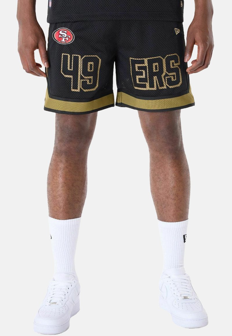 Pantalones cortos de baloncesto de malla negros con ribete dorado, que presentan grandes letras amarillas "49ERS" y un parche del logo del equipo en rojo. Usados con calcetas blancas y zapatillas.