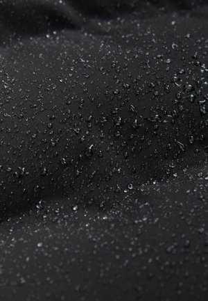 Gestructureerde zwarte stof met waterdruppels op het oppervlak, wat wijst op waterbestendigheid. Het materiaal lijkt glad met een matte afwerking.