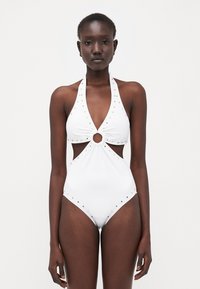 Costume intero bianco con collo all'americana, lati a taglio, dettaglio circolare al centro e accenti in metallo dorato lungo i bordi. Tessuto dalla superficie liscia.