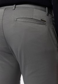 Graue Hose mit glatter Textur, Slim Fit und einer dezenten Gesäßtasche mit kleinem Markenetikett. Ideal für lässige oder smart-casual Outfits.