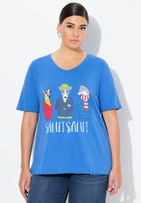 Camiseta de cuello en V azul de tela suave con gráficos de animales de dibujos animados: un gato, un perro y un lobo que llevan suéteres coloridos, con el texto "SALUT SALUT".