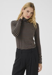 Gestreifter Rollkragenpullover in Dunkelbraun und Schwarz. Figurbetontes Design mit langen Ärmeln und weicher Textur. Kombiniert mit maßgeschneiderten schwarzen Hosen.