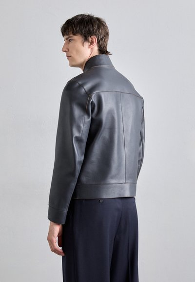 Graue Lederjacke mit einem strukturierten Kragen, kontrastierenden Nähten und glatter Textur, taillenkurzer Schnitt.