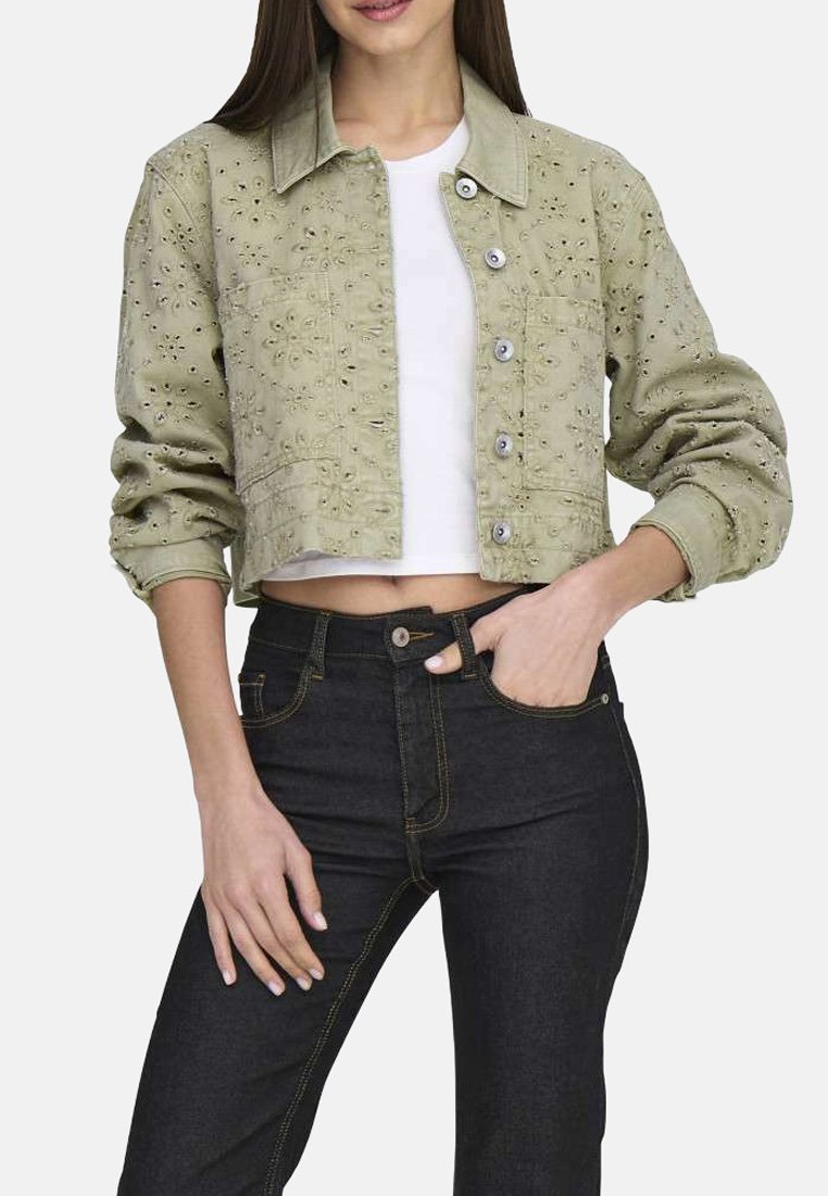 Veste en denim vert clair, courte, avec broderie, fermeture à boutons et deux poches avant. Portée par-dessus un haut blanc et associée à un jean foncé.