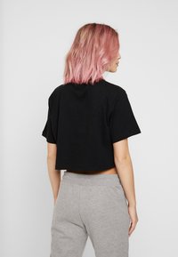 Svart kortärmad t-shirt i bomull, kombinerad med grå sweatpants, vilket ger en enkel och avslappnad stil.