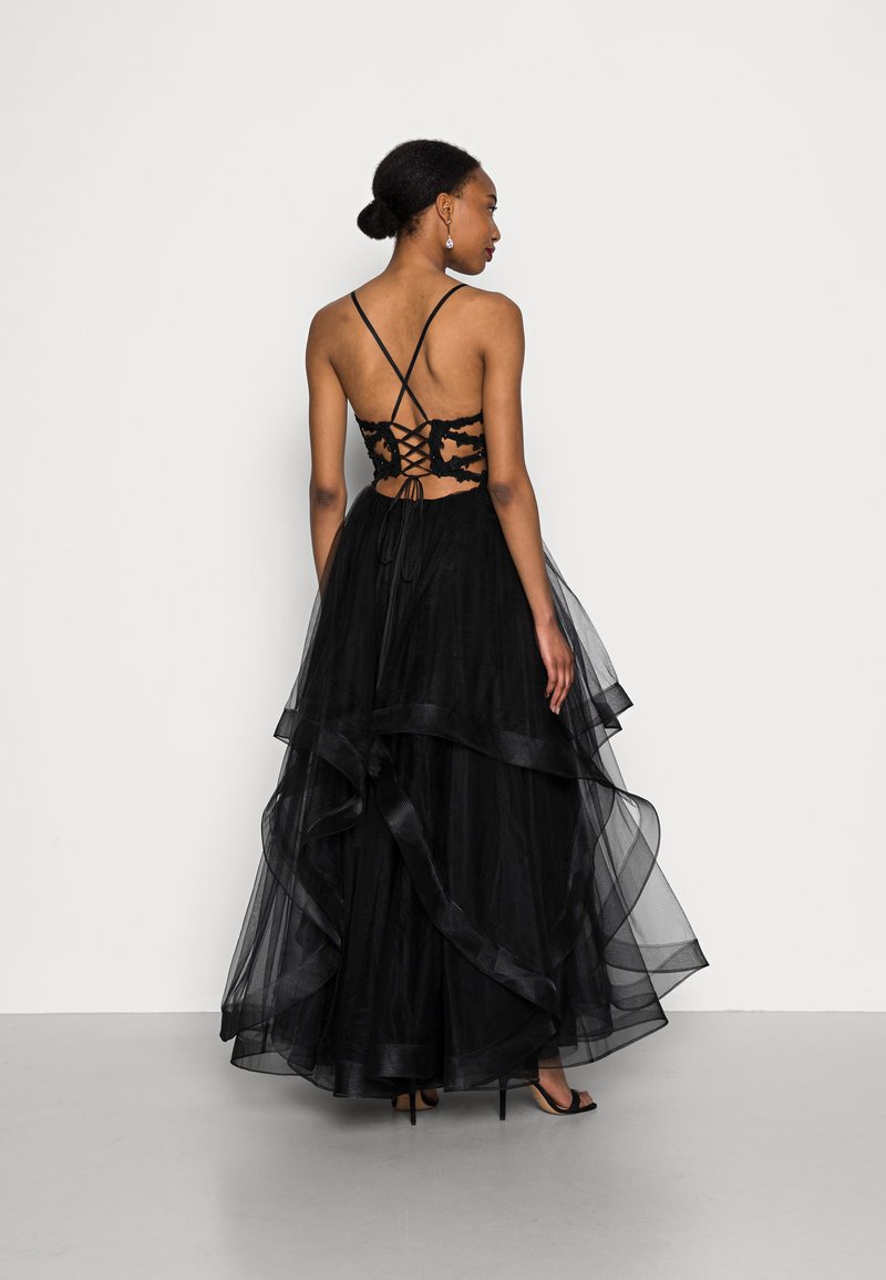 Abito in tulle nero con gonna a strati e schiena lacciata. Caratterizzato da spalline sottili e un design trasparente e testurizzato.