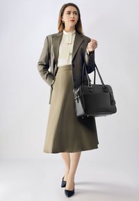 Sort læderhåndtaske med dobbelte håndtag og guldfarvet hardware, parret med en skræddersyet olivengrøn nederdel og en cremet bluse. Ensfarvet.