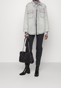 Džínová bunda ve světlé šedé barvě, má dvě kapsy a knoflíky. Nositá přes černé tričko s dlouhým rukávem, spárovaná s tmavými džíny a černými botami na podpatku.