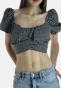 Sort-hvid ternet cropped top med pufærmer, flæsedetalje ved udskæringen og figursyet talje, kombineret med højttaljede denimshorts.