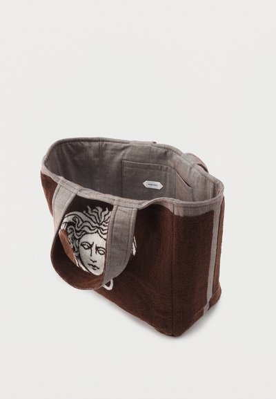 Καφέ και γκρι τσάντα ώμου με σχέδιο κεφαλής Μέδουσας στο πλάι, εσωτερική θήκη με ετικέτα Versace, κατασκευασμένη από υφασμάτινο ύφασμα.