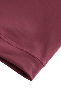 Burgundy tyg med en slät yta och subtil glans. Har platta sömmar och en vikt fåll för en ren finish.