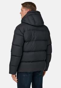 Svart vadderad jacka med huva, med en quiltad design, mjuk textur och elastiska muddar, stylad med en avslappnad passform.