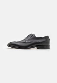 Scarpa da uomo in pelle nera con finitura liscia, punta arrotondata, design semplice, sei fori per i lacci e tacco basso impilato.