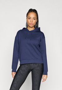 Sweatshirt azul-escuro com bolso canguru e capuz ajustável, feito de um tecido suave com um corte descontraído. Combinado com leggings pretas estampadas.