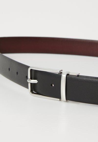 Juodas odinis diržas su lygiu paviršiumi, sidabriniu stačiakampiu sagtimi ir keliais reguliavimo skylutėmis. Vidinė dalis yra bordo spalvos.