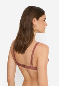 Σουτιέν σε μωβ απόχρωση με ρυθμιζόμενες τιράντες, λείο ύφασμα και κλείσιμο με άγκιστρο στην πλάτη. Διακριτική γυαλάδα, χωρίς ραφές σχεδίαση.