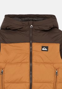 Padded jacket featuring a brown hood and upper section, with an orange lower body. Includes a central zipper and side pockets.