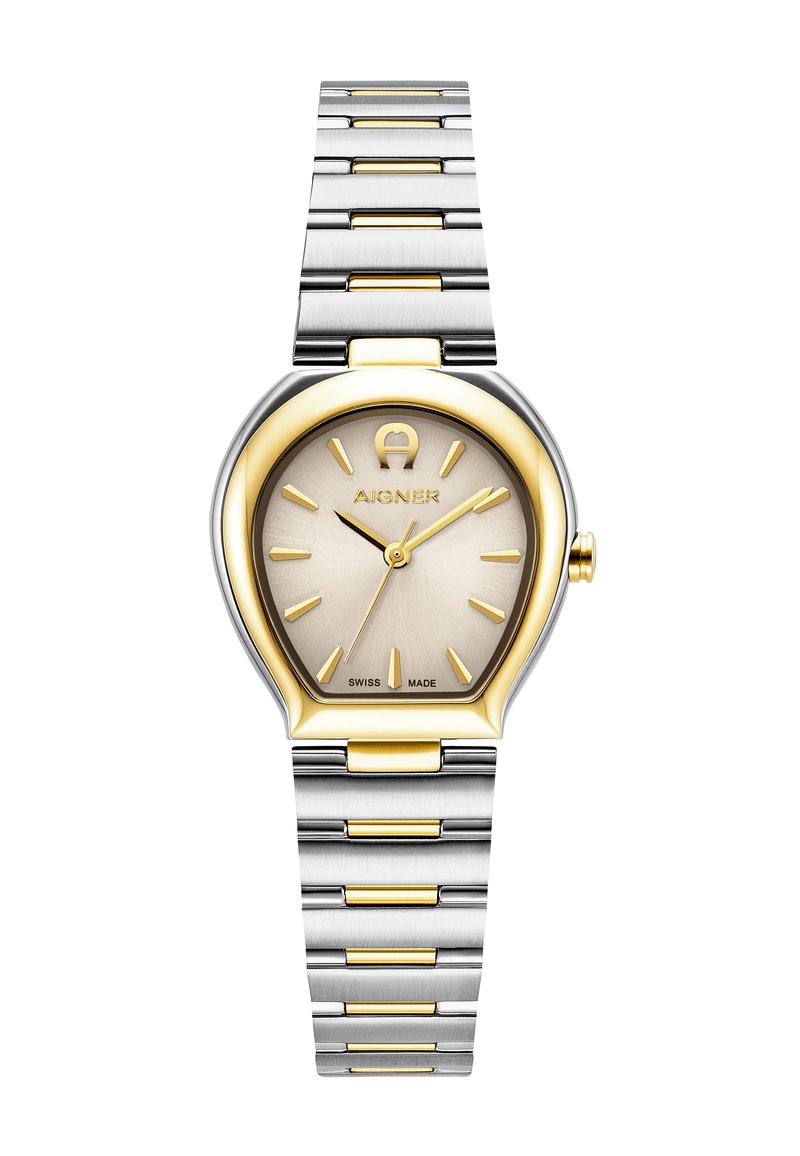 Zelta un sudraba nerūsējošā tērauda pulkstenis ar unikālu asaru formas korpusu, teksturētu šampanieša krāsas ciparnīcu, zelta stundu rādītājiem un Šveices ražojuma marķējumu.