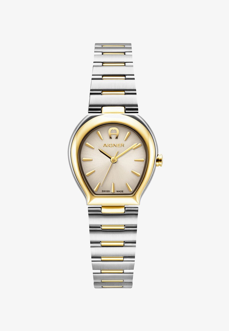 Zelta un sudraba nerūsējošā tērauda pulkstenis ar unikālu asaru formas korpusu, teksturētu šampanieša krāsas ciparnīcu, zelta stundu rādītājiem un Šveices ražojuma marķējumu.