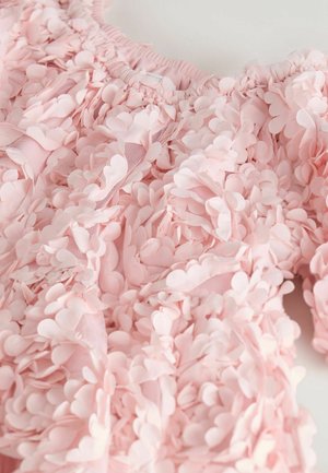 Bluza roz din țesătură decorată cu ornamente suprapuse în formă de petale; gât adunat; textură moale; bază transparentă vizibilă prin zonele mai deschise la culoare.