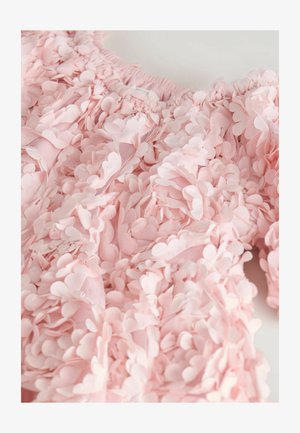 Roza tkanina na vrhu ukrašena preklapajućim ukrasima u obliku latica; zgusnuti izrez; mekana tekstura; prozirna osnova vidljiva kroz svjetlija područja.