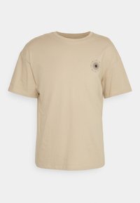Beige Baumwoll-T-Shirt mit kurzen Ärmeln, Rundhalsausschnitt und einem Sonnenstrahlen-Graphic, das auf der linken Brust aufgedruckt ist. Glatte Textur.
