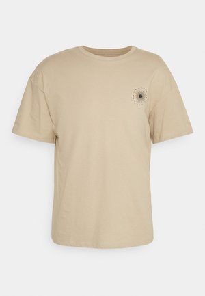T-shirt en coton beige à manches courtes, col rond, avec un motif en rayons de soleil imprimé sur la poitrine gauche. Texture lisse.