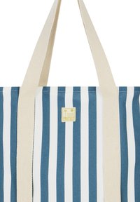 Blauw-wit gestreepte boodschaptas met beige canvas handvatten en een klein geel logo-embleem met een zon- en waterafbeelding.
