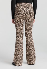 Pantaloni a zampa d'elefante con stampa leopardata su sfondo beige, caratterizzati da una texture liscia e una vita elastica, progettati per un look aderente.