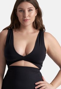 Zwart badpak met een diepe V-halslijn en brede banden. Heeft een uitsnijding bij de taille en een gladde, rekbare textuur.