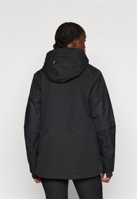 Casaco impermeável preto com um corte solto, com capuz, tecido texturizado, mangas longas e mangas escuras contrastantes.